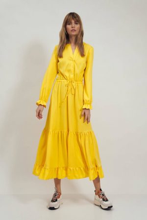 Długa żółta sukienka koszulowa z falbanką.